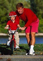 Fotografía de un padre que le está enseñando a montar en bicicleta a su hijo