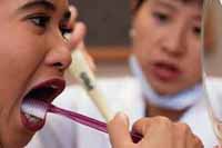 Fotografía de un dentista enseñandole a una niña como cepillarse los dientes de una forma adecuada