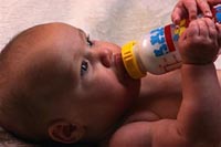 Fotografía de un bebé tomando leche de biberón por si mismo