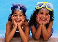 Fotografía de dos niñas sonriendo al lado de la piscina
