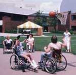 Fotografía de personas con problemas en el desarrollo, en sillas de ruedas, que estan jugando baloncesto