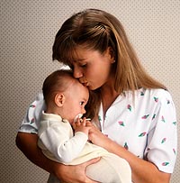 Fotografía de una mujer besando a su bebé en la frente
