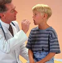 Fotografía de un médico examinando la garganta de un niño pequeño
