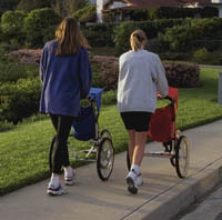 Fotografía de dos madres caminando con un coche para trotar
