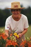 Picture of elderly woman, wearing a wide-brimmed hat, gardening