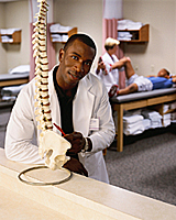 Picture of a physician and a model of a human spine
