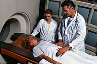 Picture of a patient in a CT scanner, with physician and technologist present