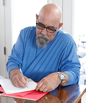 Man sitting at table, writing.