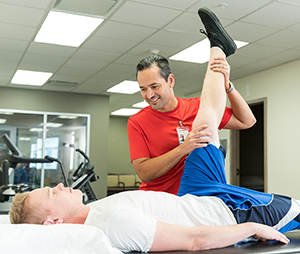 Physical therapist working with man on leg stretches.
