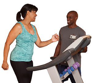 Man coaching woman walking on treadmill.