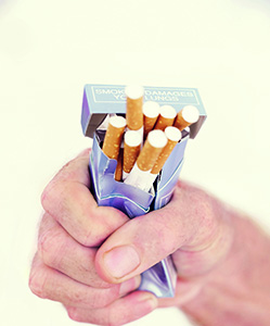 Photo of a man's hand crushing a pack of cigarettes in his fist