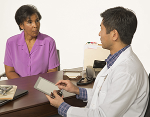 Healthcare provider with electronic tablet talking to woman.