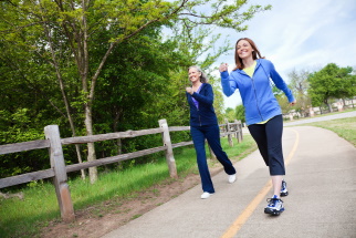 Two women power walking on a park trail