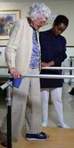 Fotografía de una anciana caminando durante una sesión de fisioterapia 