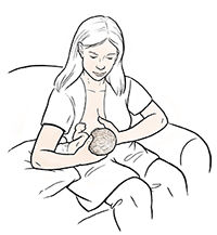 Woman breastfeeding baby in football hold.