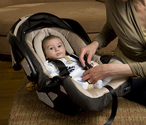 Woman securing baby in carrier.